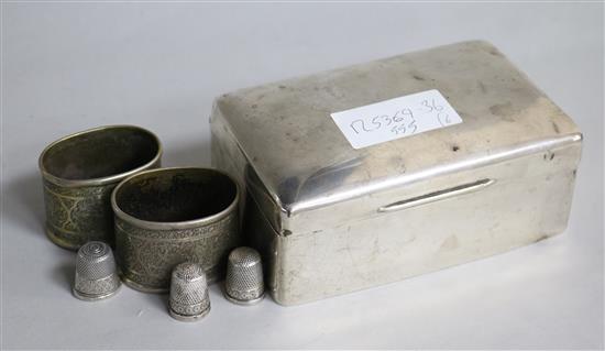 A silver cigarette box, three sterling silver thimbles and two metal napkin rings.